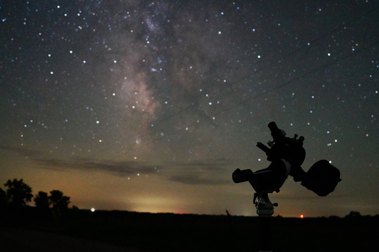 Telescope pointed towards a starry night sky with the Milky Way visible.