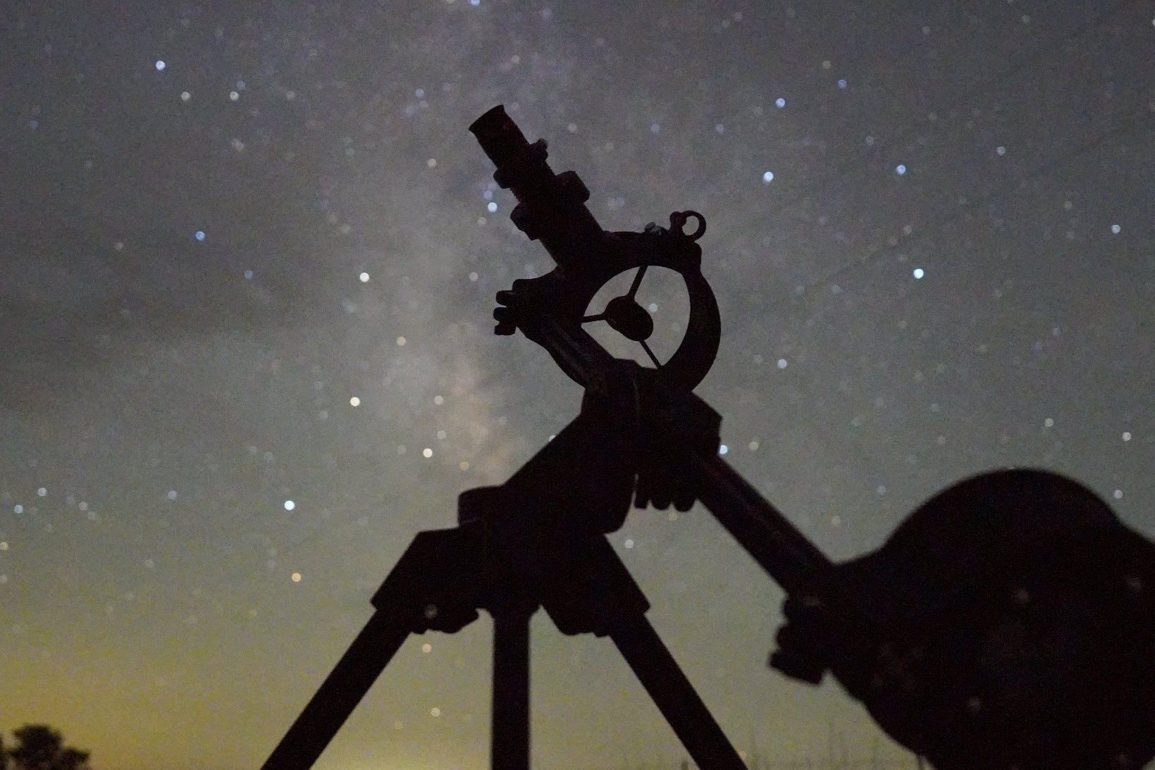 Silhouette of travel telescope against a starry night sky